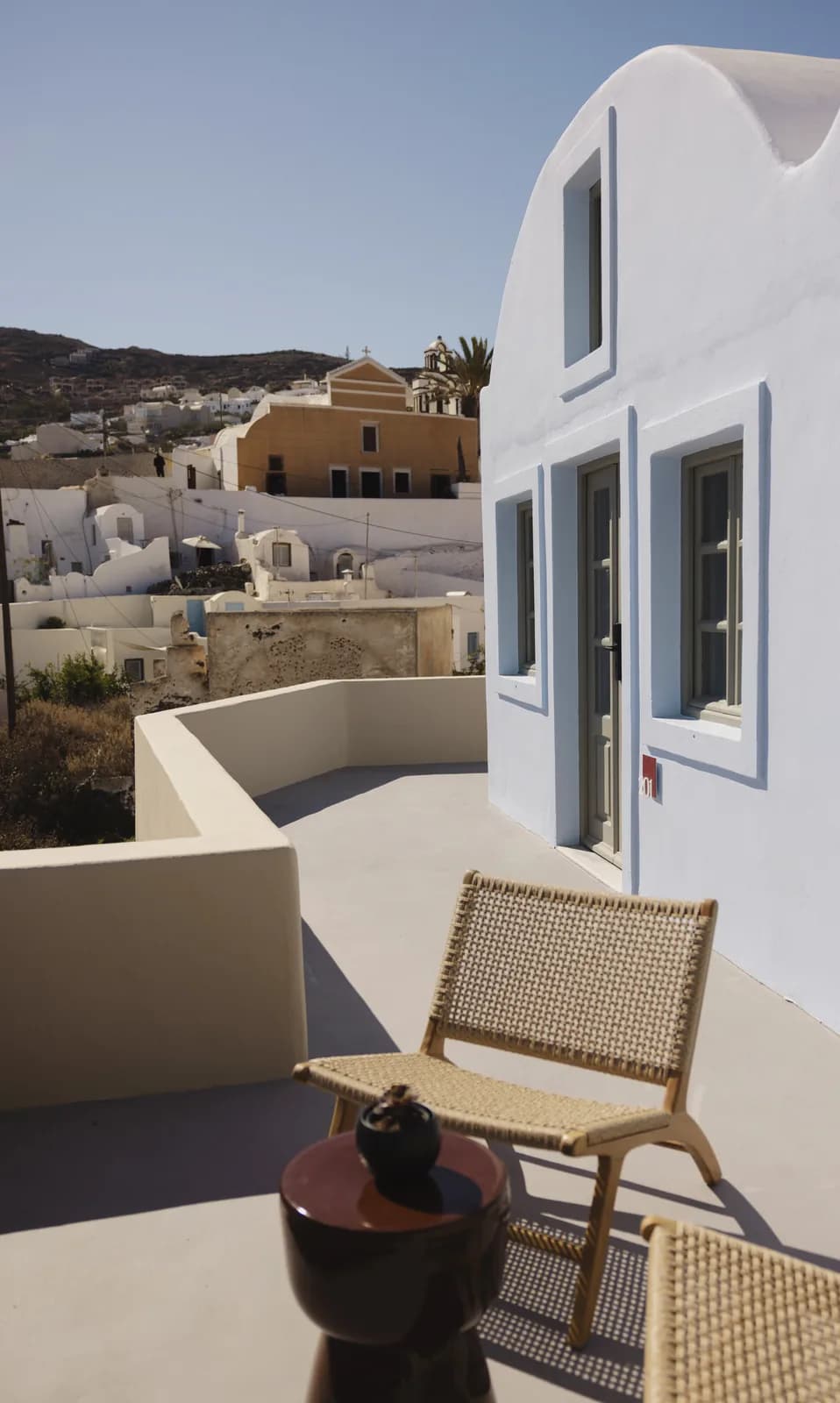 Stuhl auf der Terrasse der Red-Carpet Cove Suite, dahinter Finikia