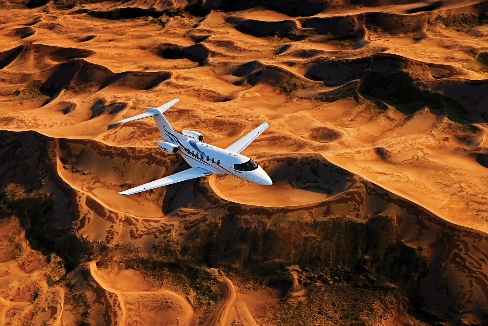 Pilatus PC-24 im Flug über Sanddünen im Abendlicht